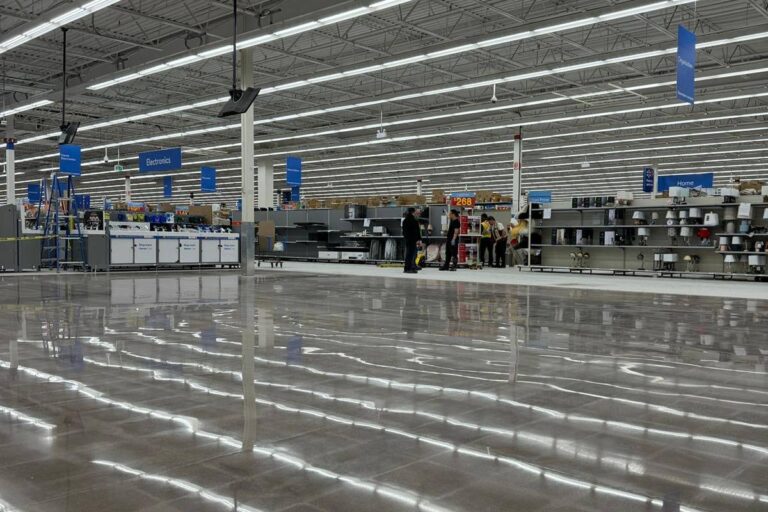 Polished concrete industrial floor reflects bright lights, modern retail store.