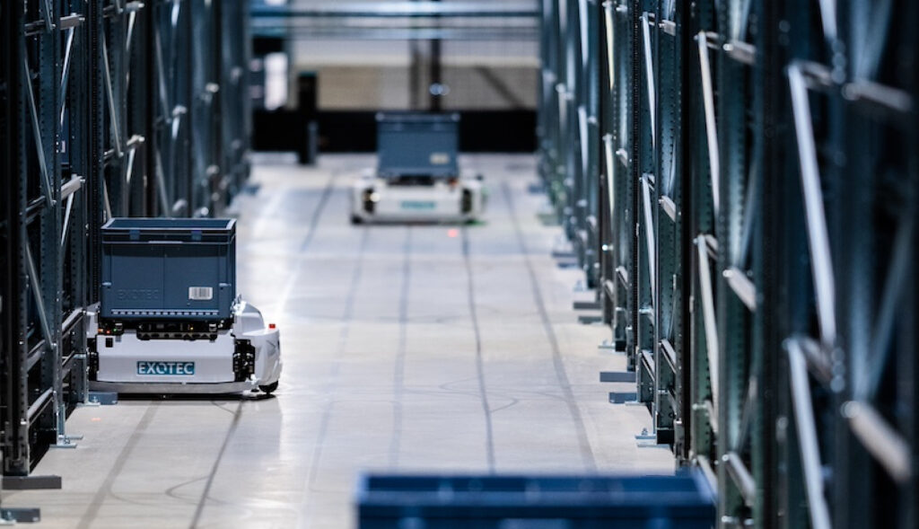 Exotec autonomous mobile robots moving containers, industrial warehouse flooring.