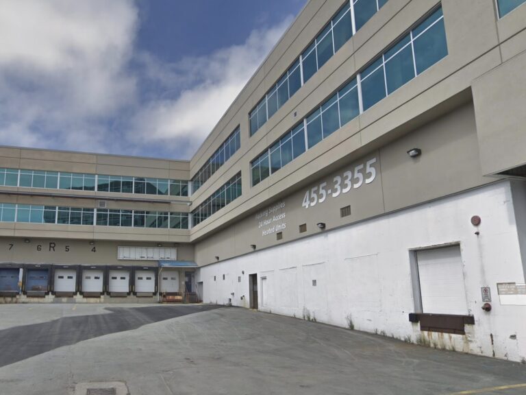 Large industrial warehouse, numerous loading docks, concrete asphalt lot.