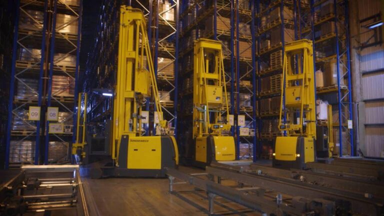 Yellow Jungheinrich forklifts operating on industrial warehouse floor between high racks.