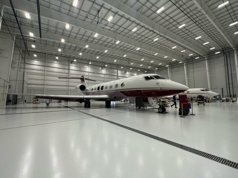 Clean aircraft hangar, private jets on reflective industrial epoxy flooring.