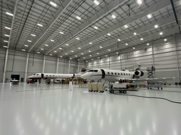 Pristine aircraft hangar, glossy gray industrial floor, private jets