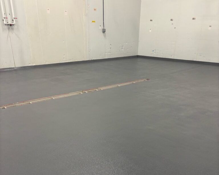 Durable gray industrial epoxy flooring with trench drain, warehouse application.