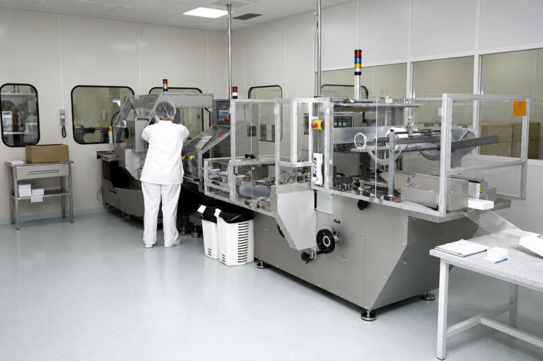 Hygienic cleanroom flooring, worker operates pharmaceutical packaging machinery.
