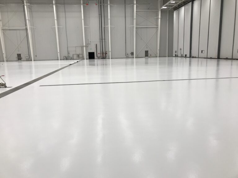 Spacious industrial facility, seamless reflective white epoxy flooring.